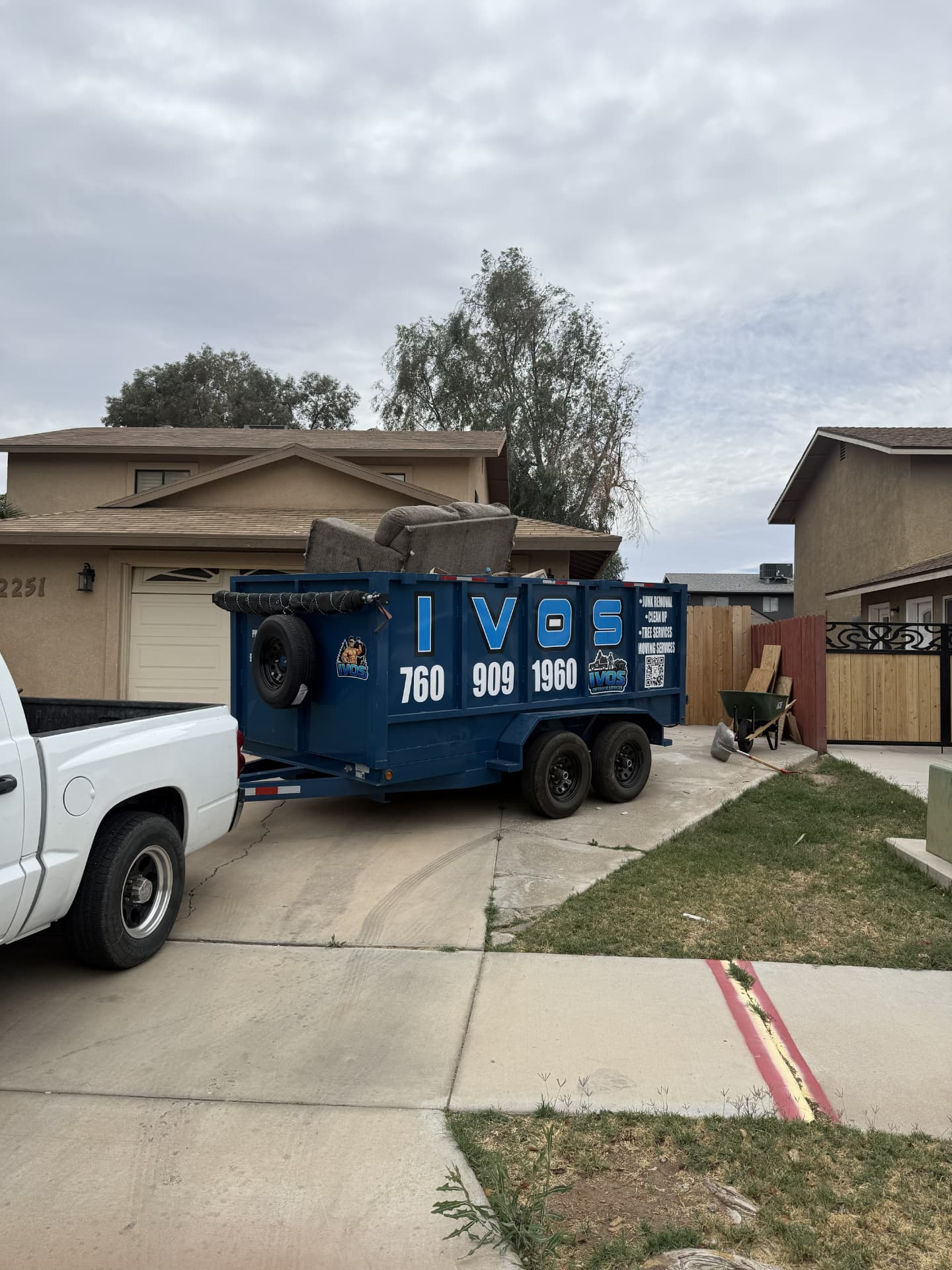 IVOS truck towing a branded blue rental trailer on a residential job